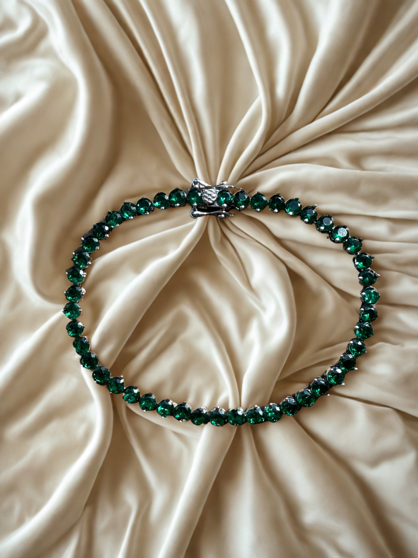 Green beaded necklace on a beige fabric surface