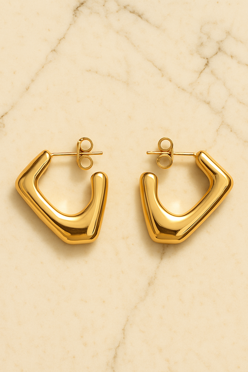Gold hoop earrings on a beige marble surface