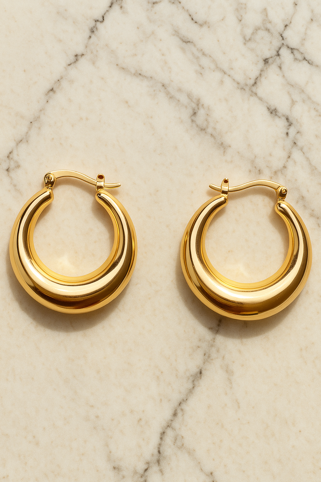 Gold hoop earrings on a marble surface