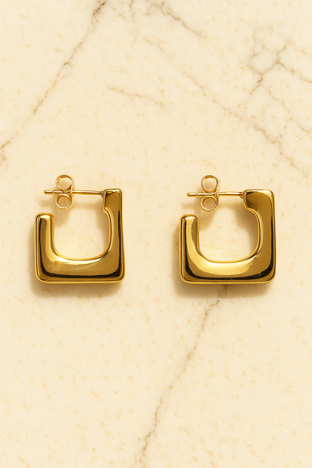 Gold hoop earrings on a beige textured background