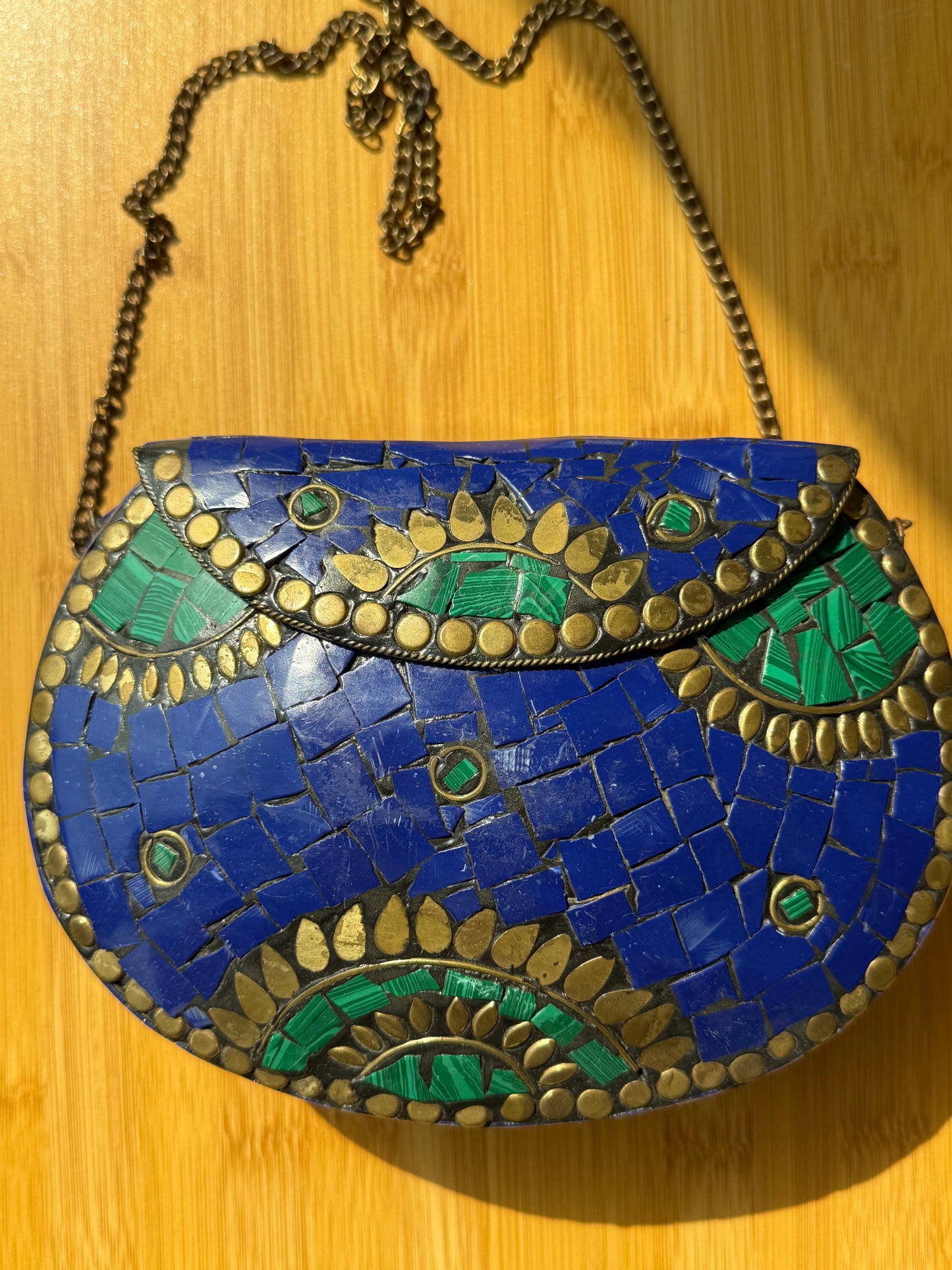 Mosaic handbag with blue and green patterns on a wooden surface