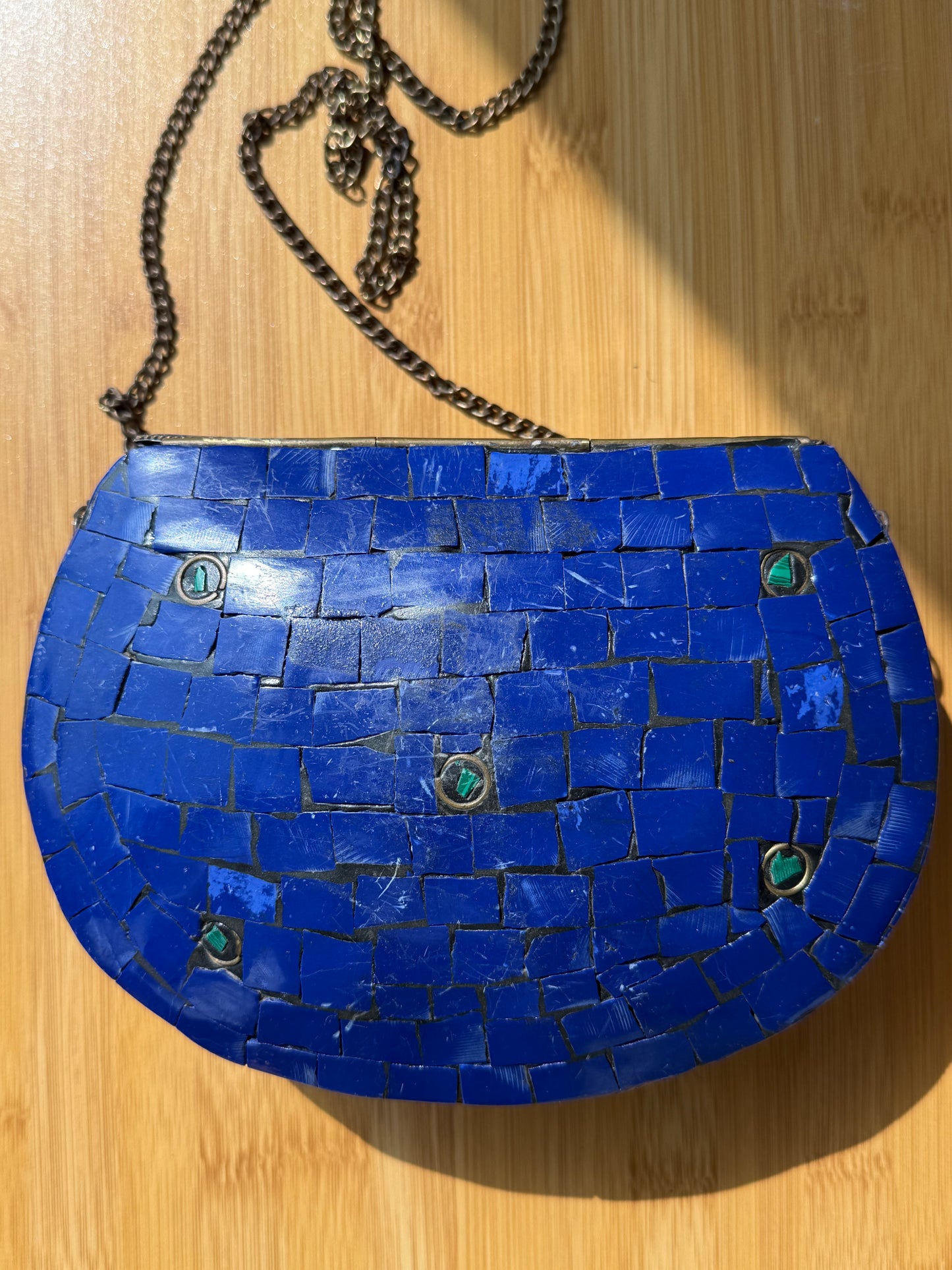 Blue mosaic handbag with a chain on a wooden surface