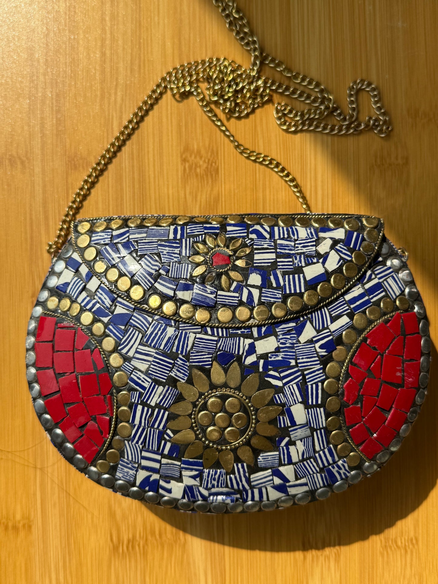 Mosaic-patterned handbag with a chain on a wooden surface