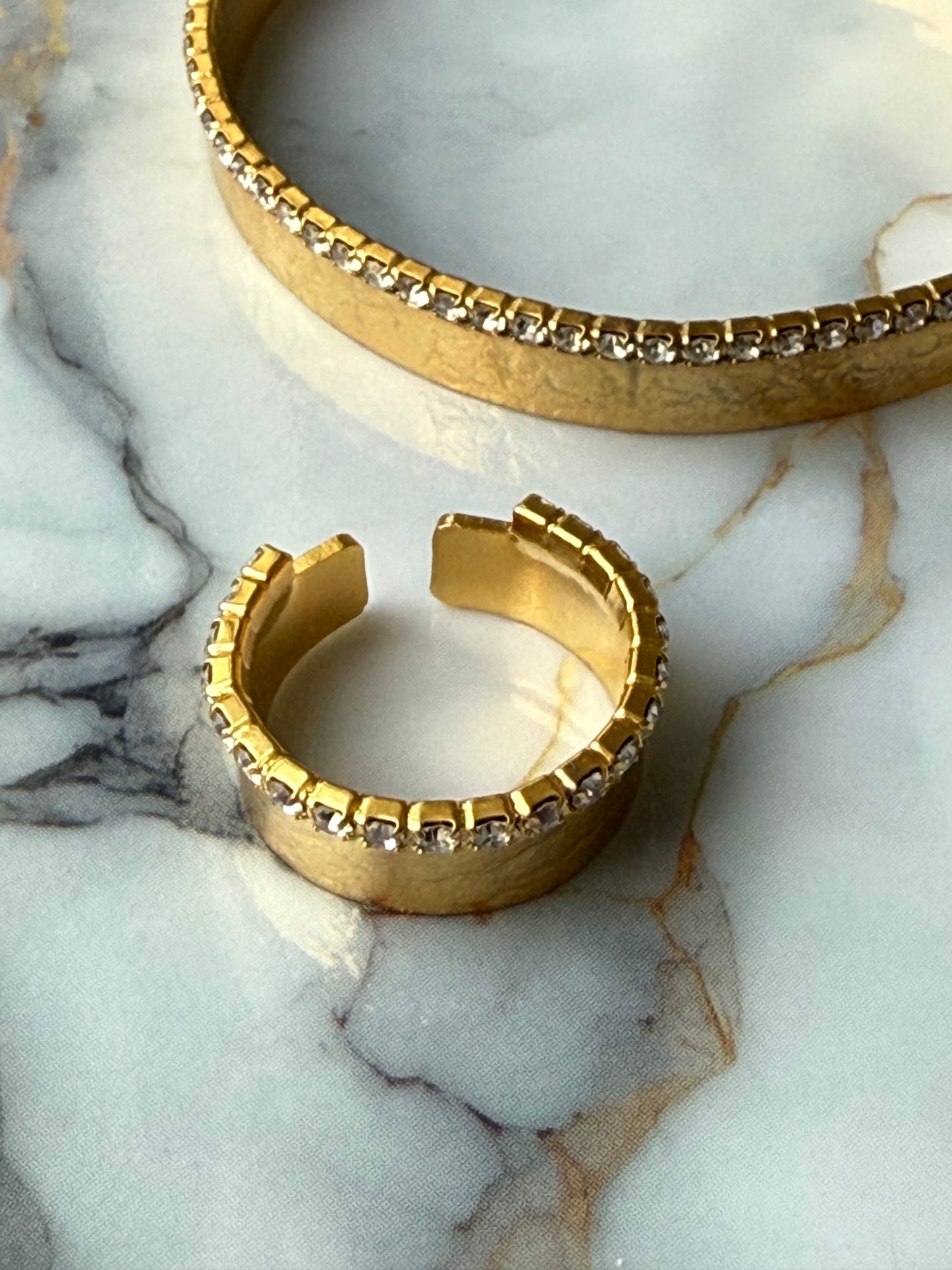 Gold-plated bangle and adjustable ring set featuring a single row of clear zirconia crystals, designed with minimalist elegance and handcrafted for Suzys Treasures, displayed on a marble background.