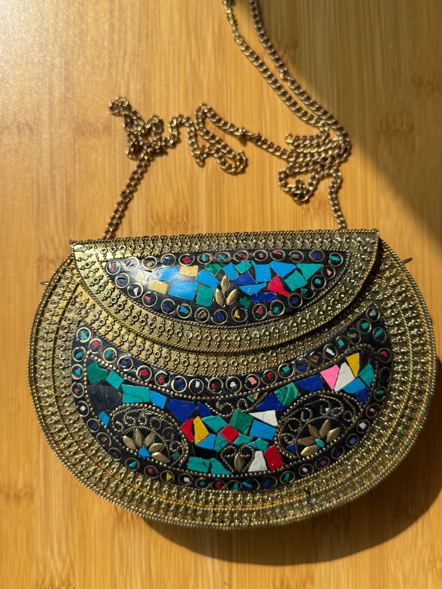 Decorative clutch with intricate patterns and colorful stones on a wooden surface