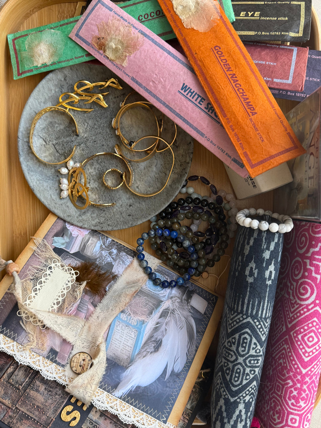 Flat lay of handcrafted jewelry, crystal bracelets, incense sticks, handmade journals, and boho yoga bags from Suzys Treasures – celebrating soulful, artisan-made products.