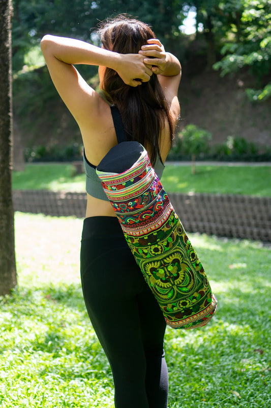 Woman carrying a colorful boho yoga bag with traditional ethnic patterns over her shoulder, standing outdoors surrounded by lush greenery – Suzys Treasures.