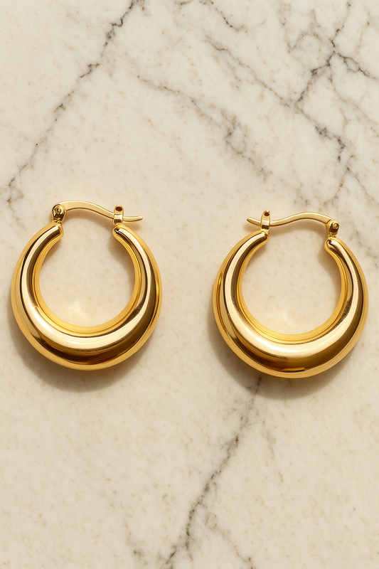 Gold hoop earrings on a marble surface