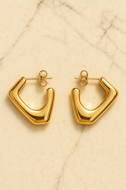 Gold hoop earrings on a beige marble surface