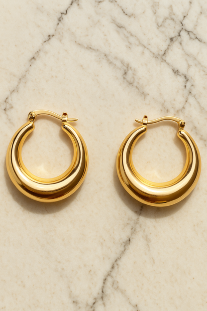 Gold hoop earrings on a marble surface