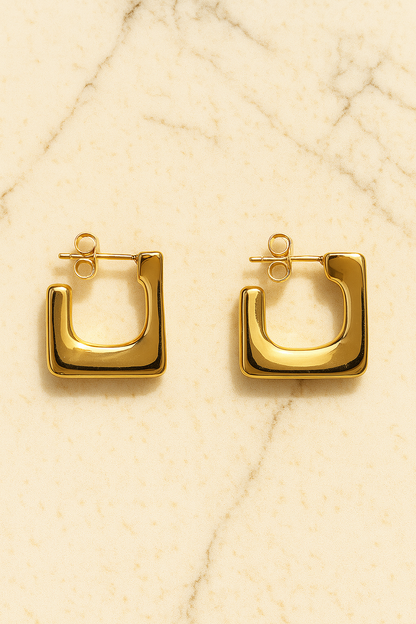 Gold hoop earrings on a beige textured background