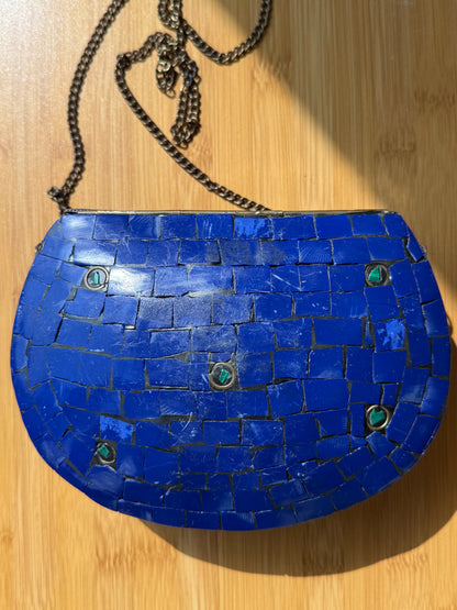 Blue mosaic handbag with a chain on a wooden surface