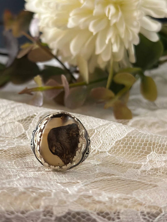 Suzys Treasures women's Yemeni dendritic agate ring with a bold organic pattern set in sterling silver, displayed on delicate lace fabric with soft floral background.