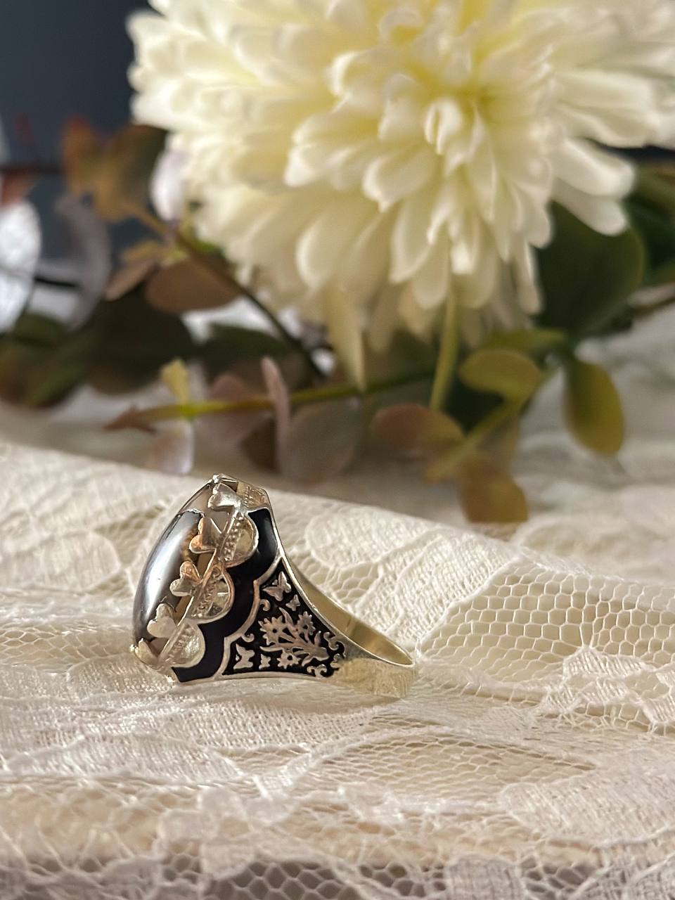 Suzys Treasures women's Yemeni dendritic agate ring with a bold organic pattern set in sterling silver, displayed on delicate lace fabric with soft floral background.