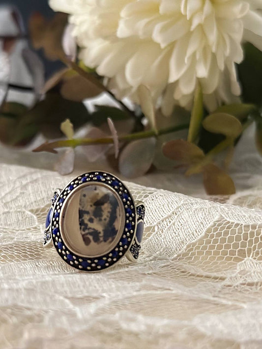 Suzys Treasures handcrafted women’s ring featuring Yemeni dendritic agate and intricate blue enamel detailing, set in sterling silver and displayed in a soft, elegant setting.