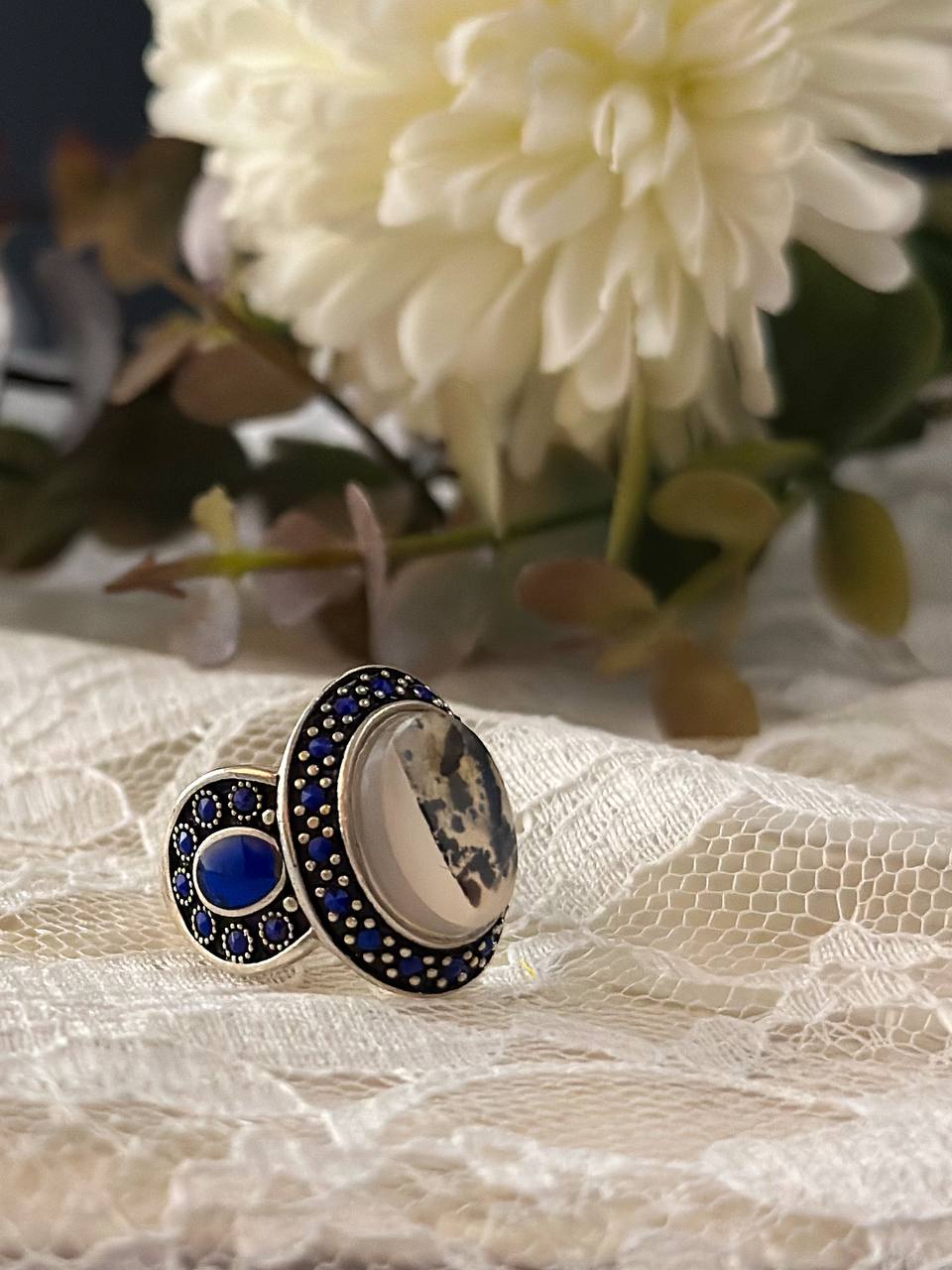 Suzys Treasures handcrafted women’s ring featuring Yemeni dendritic agate and intricate blue enamel detailing, set in sterling silver and displayed in a soft, elegant setting.