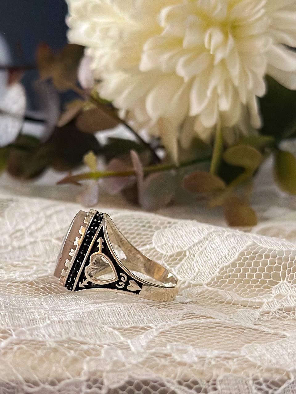 Suzys Treasures handcrafted Yemeni dendritic agate sterling silver ring, symbolizing growth and elegance, displayed on lace fabric with soft floral background.