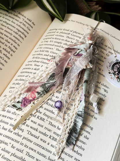 Handmade Boho tassel paperclip bookmark from Suzys Treasures, featuring pink and gold lace ribbons, pearl bead accents, and crochet trim, displayed on an open book – a charming and versatile accessory for journals, planners, or novels.