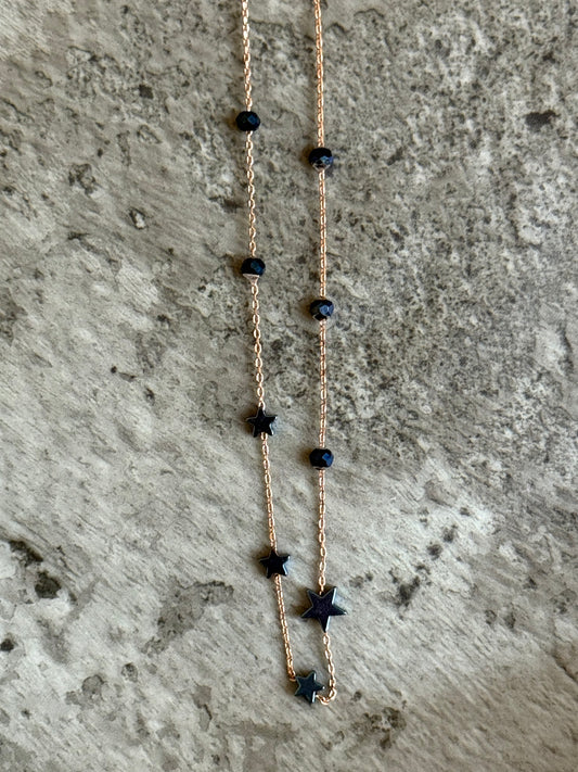 Suzys Treasures handcrafted short necklace with blue hematite stars and beads on a silver embossed, 3-micron rose gold-plated chain, displayed on a textured stone background.