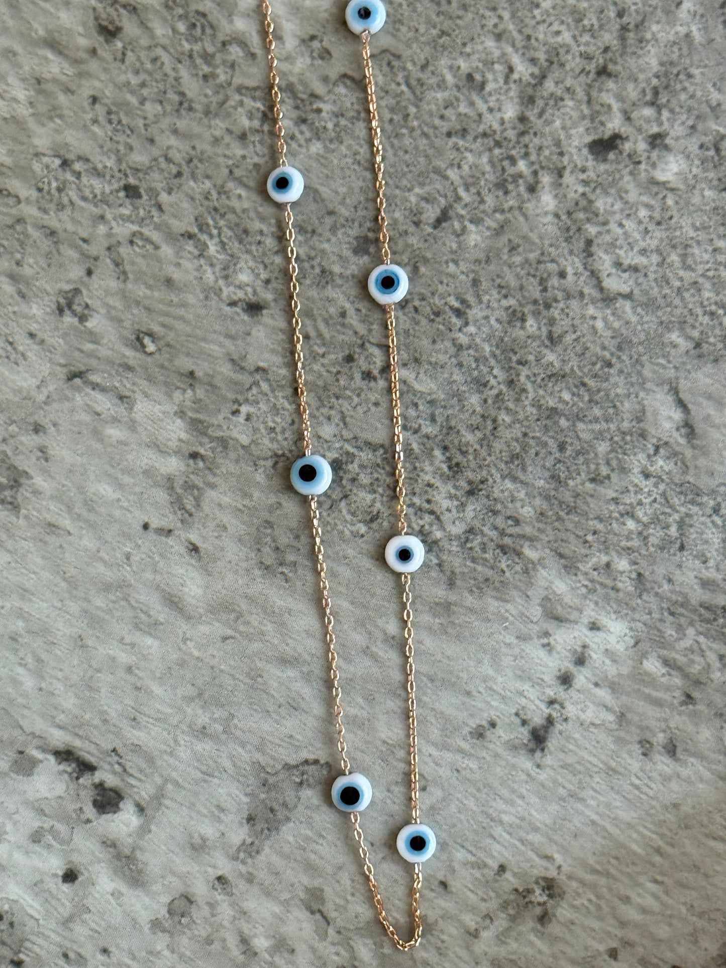 Suzys Treasures handcrafted short necklace with a Murano glass eye pendant on a silver embossed, warm-toned 3-micron plated chain, displayed on a textured stone background.