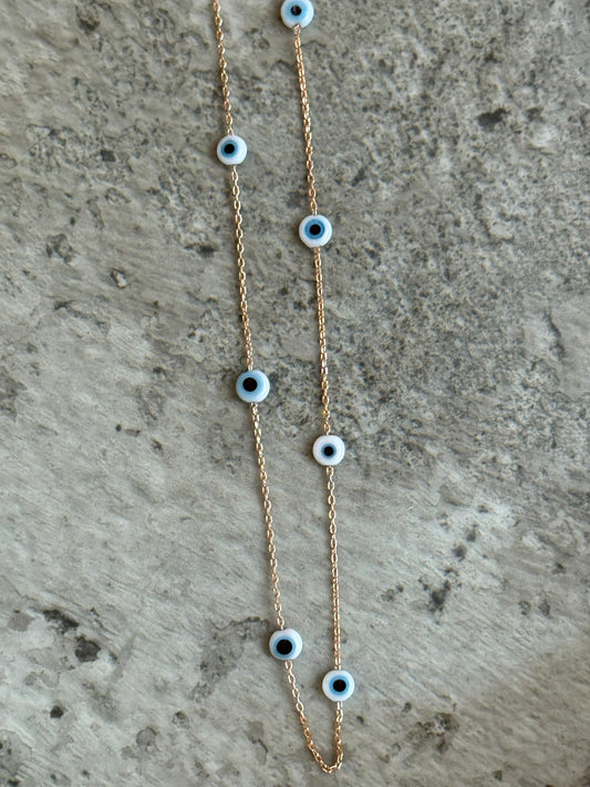 Suzys Treasures handcrafted short necklace with a Murano glass eye pendant on a silver embossed, warm-toned 3-micron plated chain, displayed on a textured stone background.