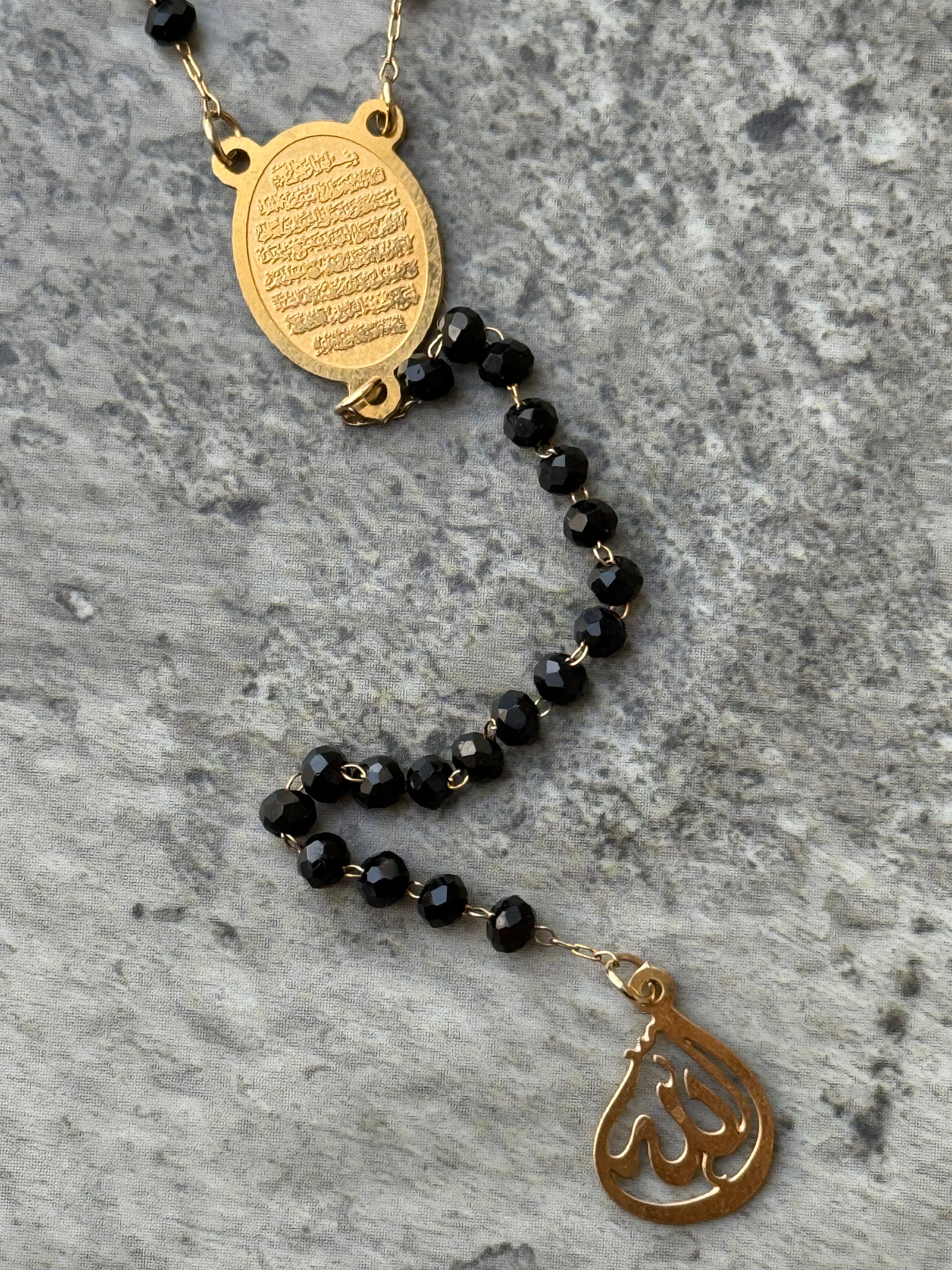 Islamic spiritual necklace with Ayat Al-Kursi engraved pendant and black beads, displayed flat from Suzys Treasures