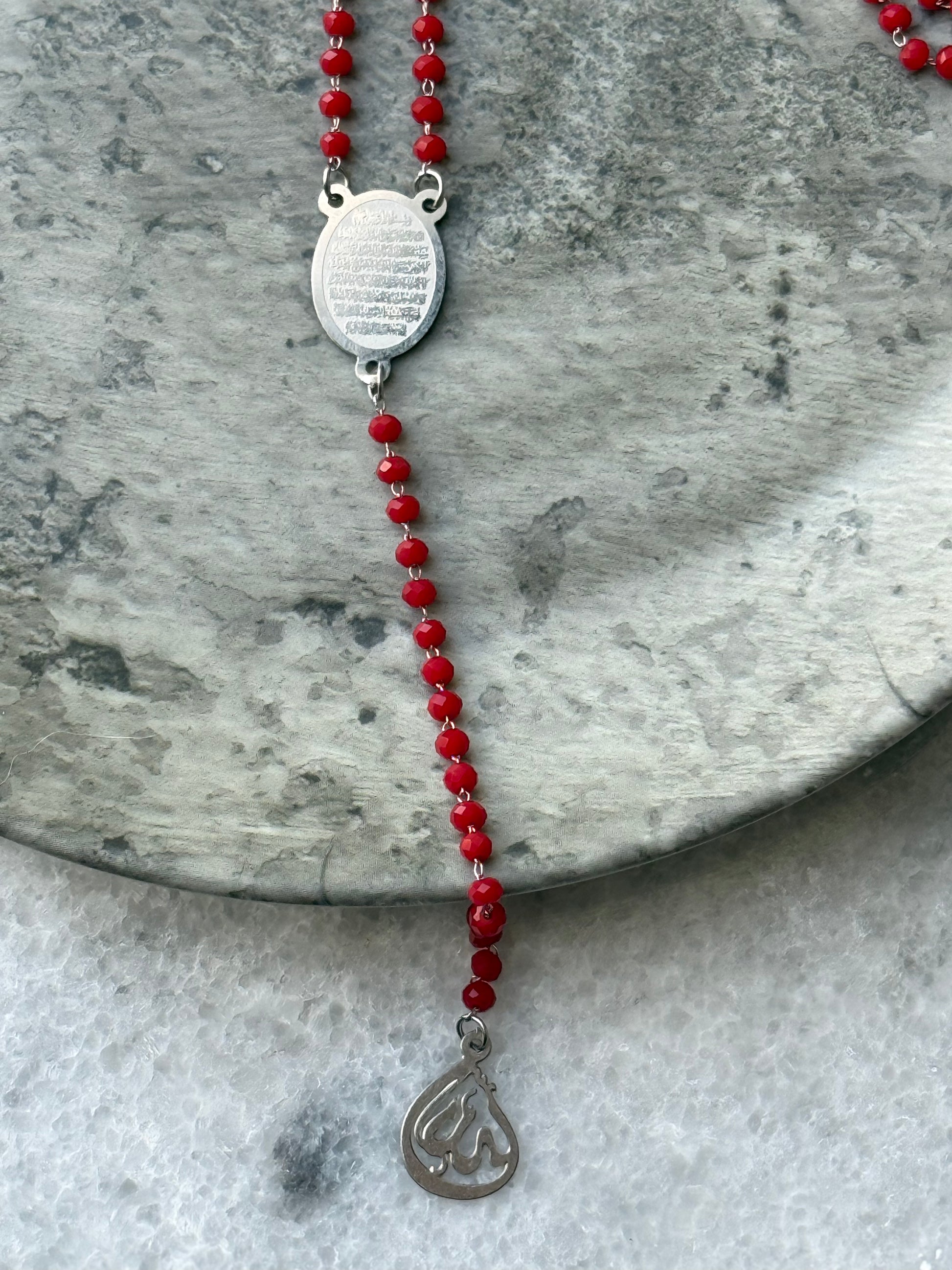 Islamic spiritual necklace with Ayat Al-Kursi engraved pendant and red beads, displayed flat - Suzys Treasures