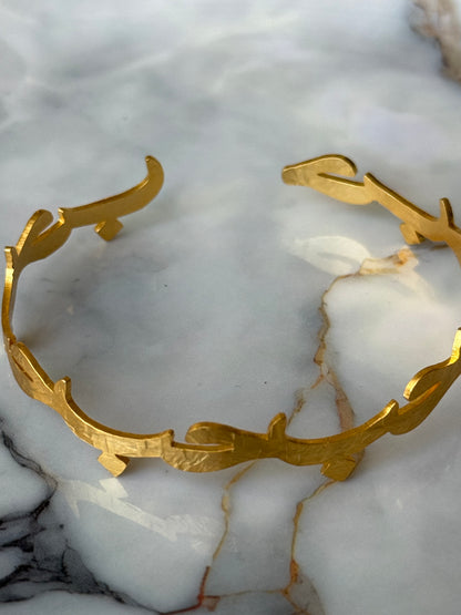 Gold-plated Arabic bangle with the word “Hub” (Love) in calligraphy, resting on a marble surface. Available at Suzy’s treasures online store. 