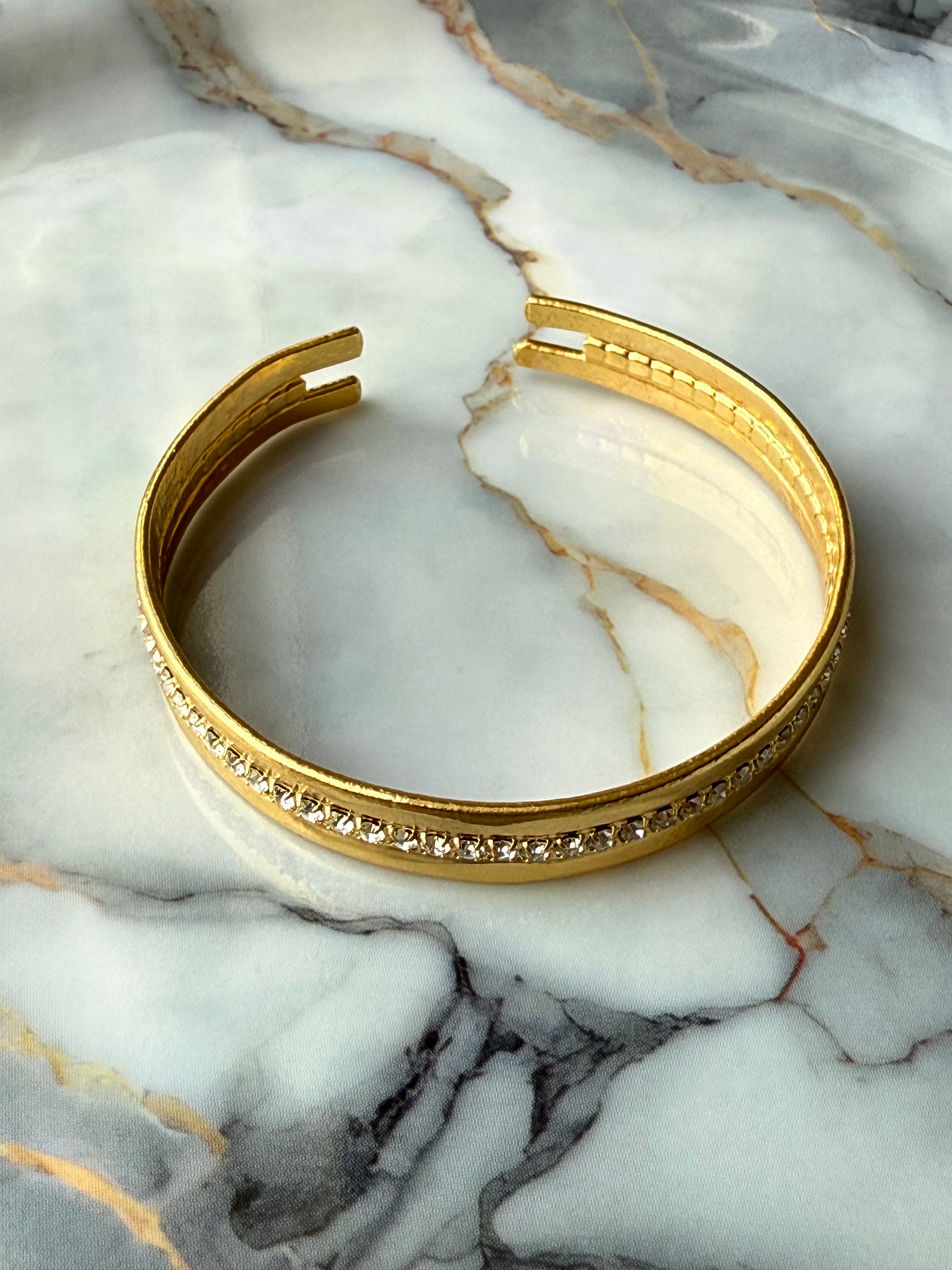 Minimalist copper bangle with single row zirconia crystals and 3-micron gold plating on marble background – Suzys Treasures