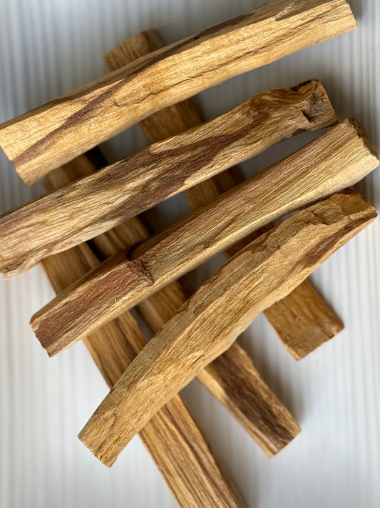 
Thick Palo Santo smudging sticks from Peru, stacked on a neutral surface, used for energy cleansing, grounding, and spiritual rituals, part of the Sacred Scents & Space collection by Suzy’s Treasures.

