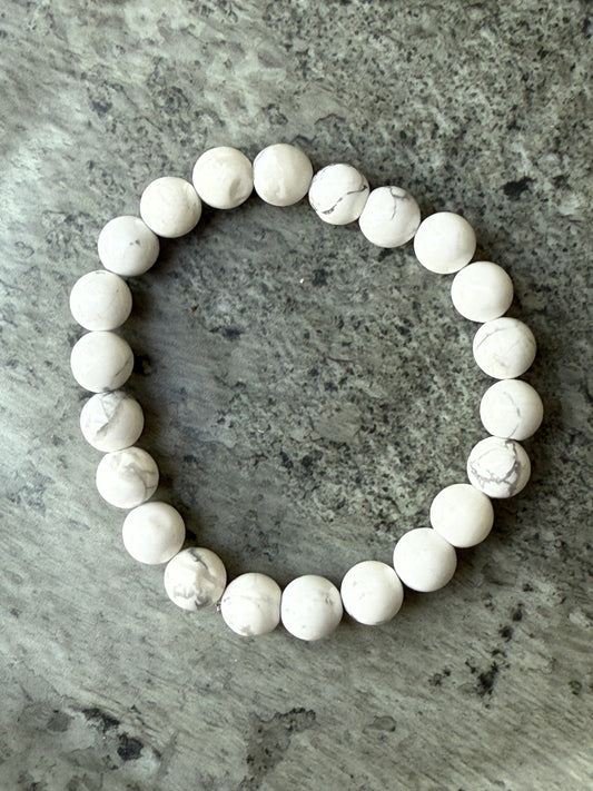Howlite round bead bracelet with white and grey marbled stones, displayed on a stone background — crystal jewelry from Suzys Treasures.