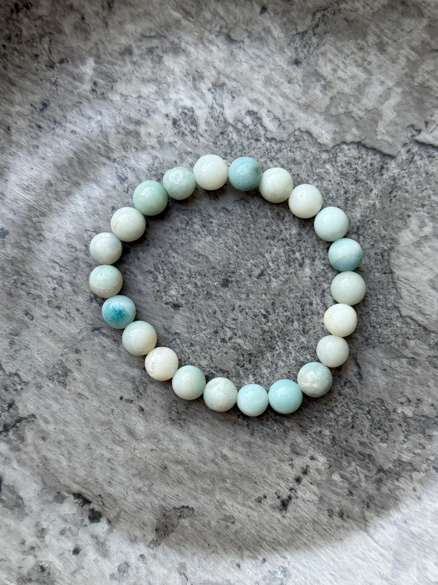 Amazonite round bead bracelet with soft green and aqua tones, displayed on a stone surface — part of the crystal jewelry collection from Suzys Treasures.