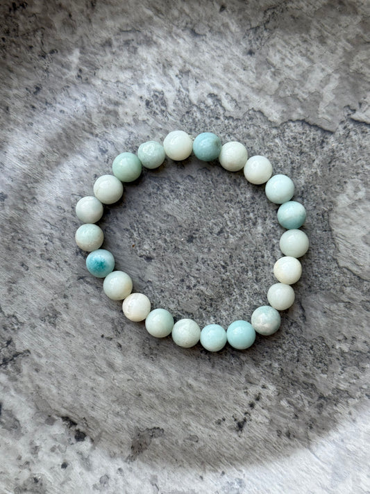 Amazonite round bead bracelet with soft green and aqua tones, displayed on a stone surface — part of the crystal jewelry collection from Suzys Treasures.