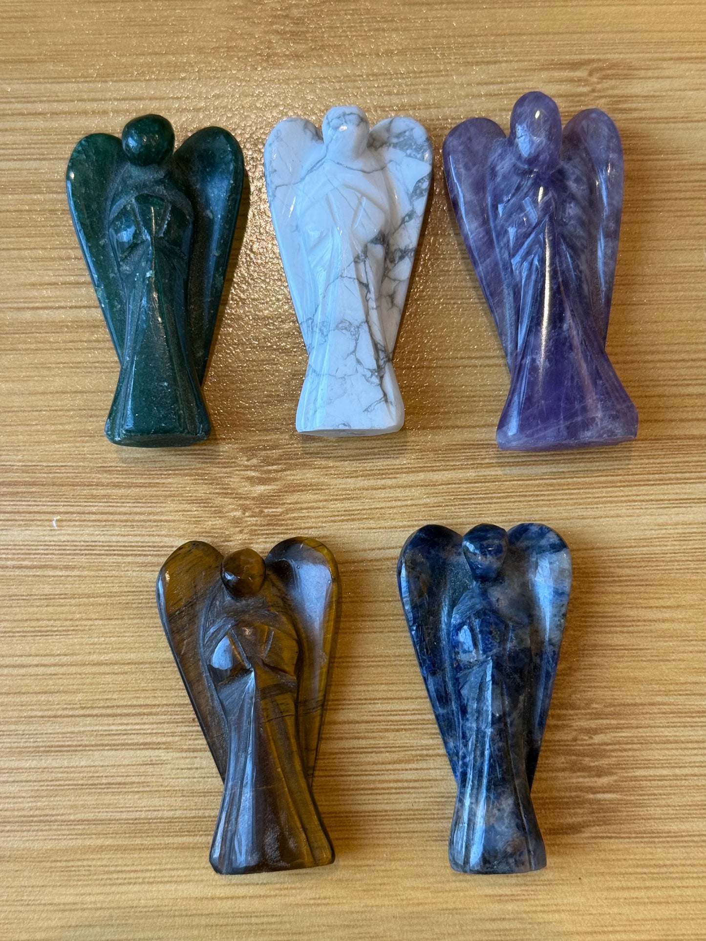 Five crystal angel figurines made of Amethyst, Howlite, Green Aventurine, Tiger’s Eye, and Sodalite on a wooden background – Suzys Treasures