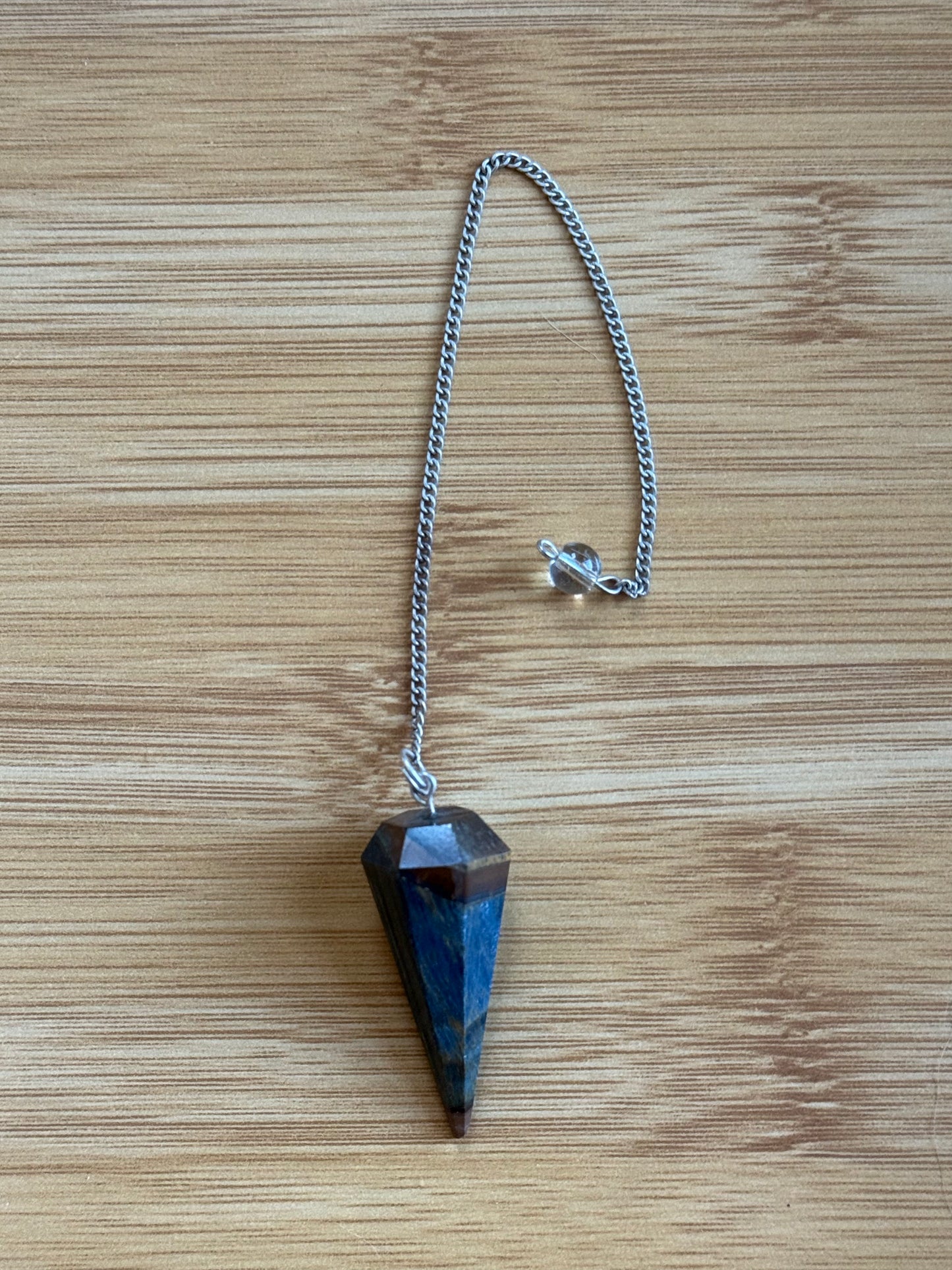 Tiger's Eye long crystal pendulum with silver chain on wooden background – Suzys Treasures