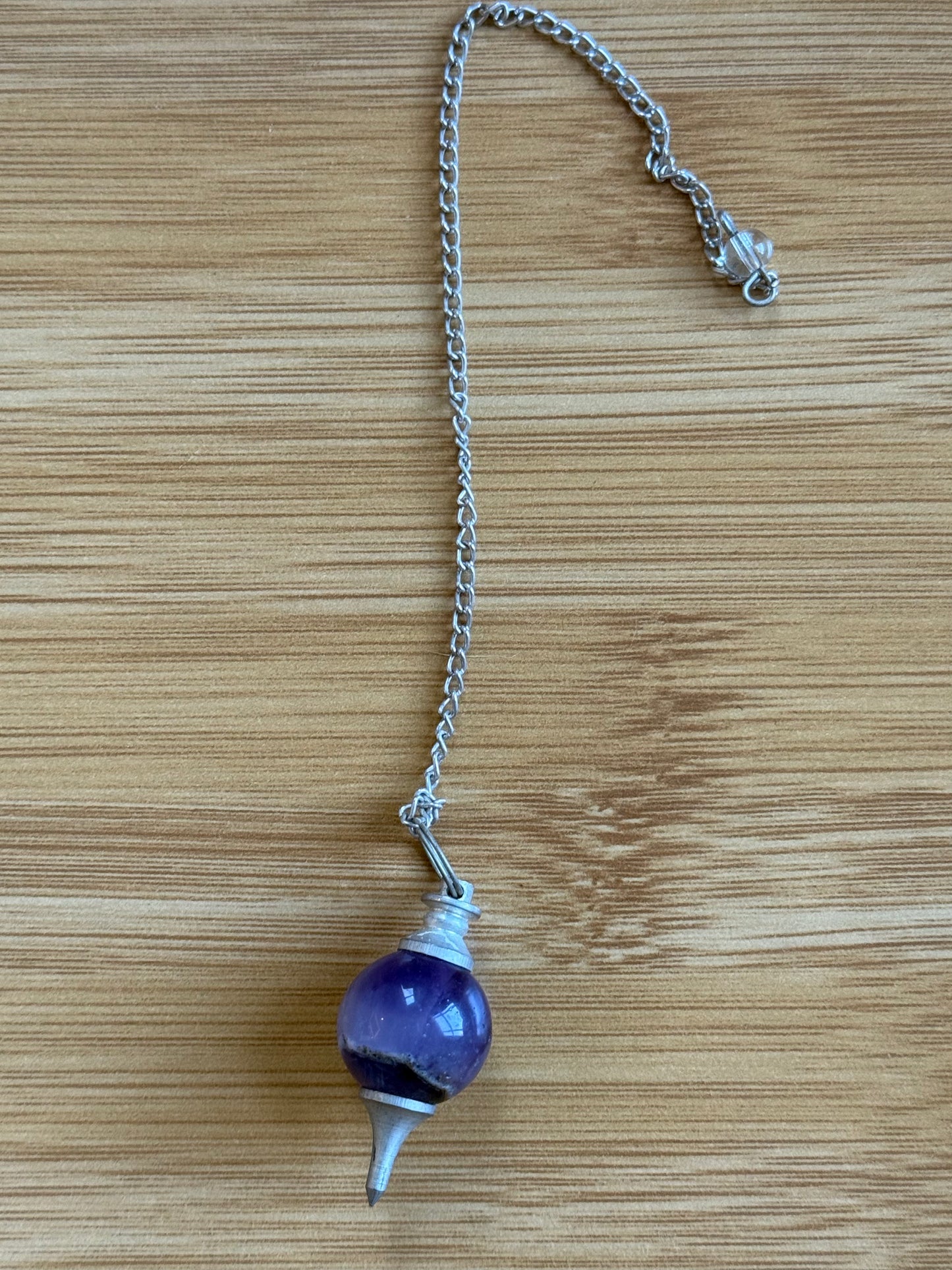 Amethyst round crystal pendulum with silver chain on wooden background – Suzys Treasures