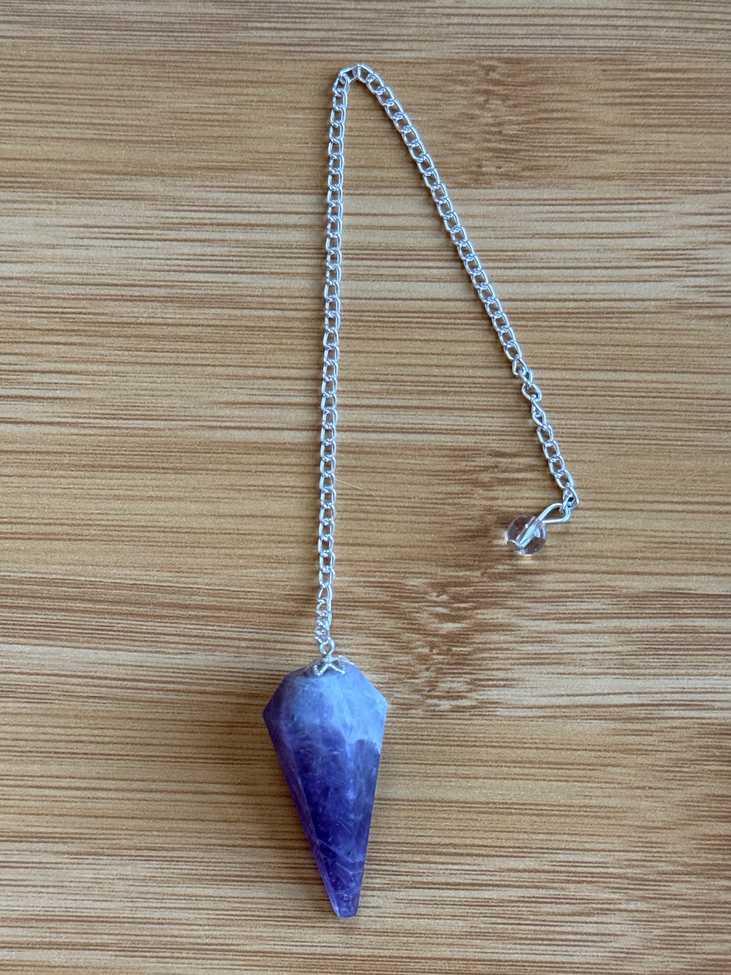 Amethyst long crystal pendulum with silver chain on wooden background – Suzys Treasures