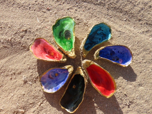 Hand-painted oyster shell dishes in vibrant colors arranged in a flower shape on the beach sand – coastal decor and sacred altar pieces from Suzys Treasures Dubai