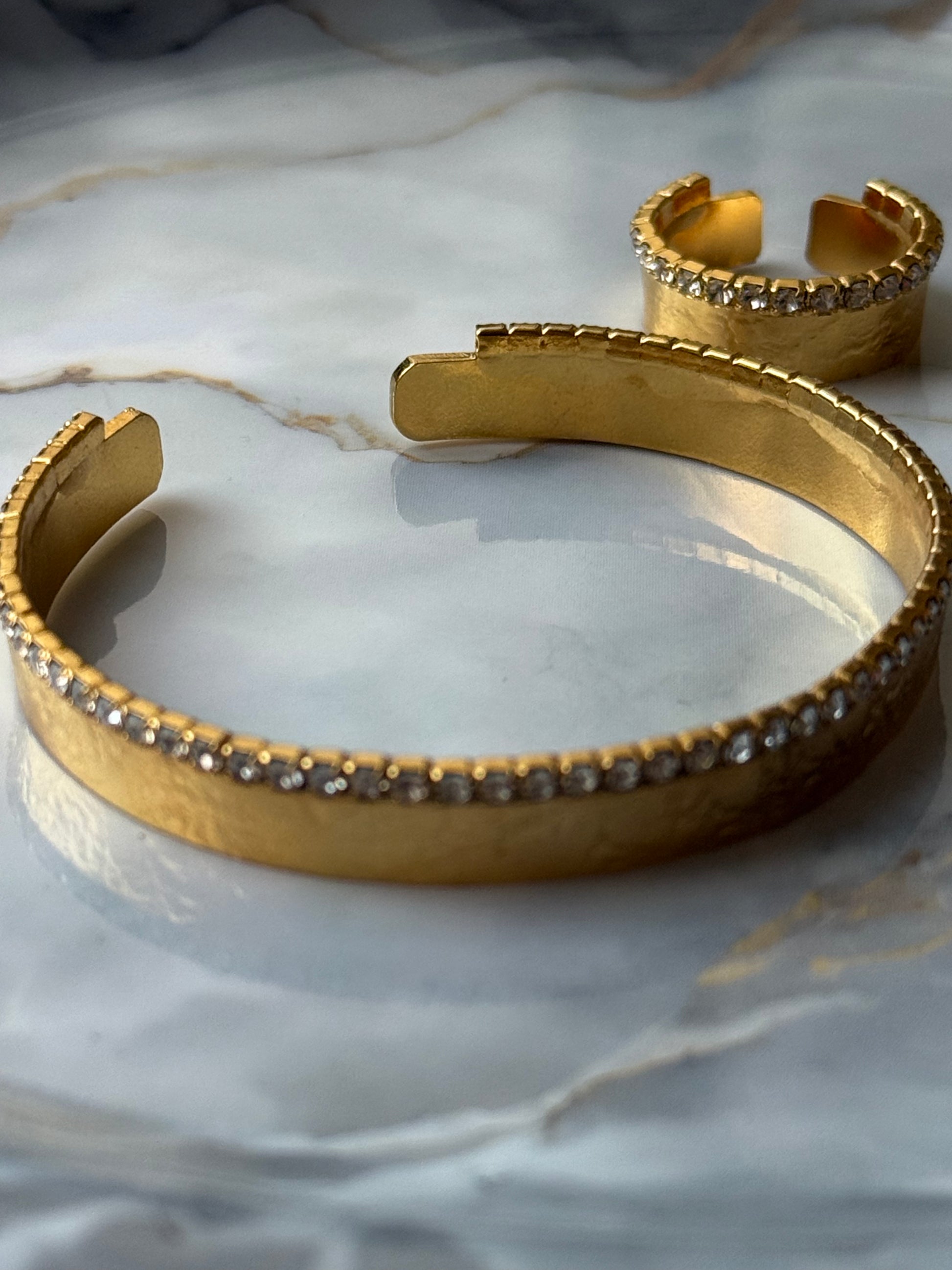 Gold-plated bangle and adjustable ring set featuring a single row of clear zirconia crystals, designed with minimalist elegance and handcrafted for Suzys Treasures, displayed on a marble background.