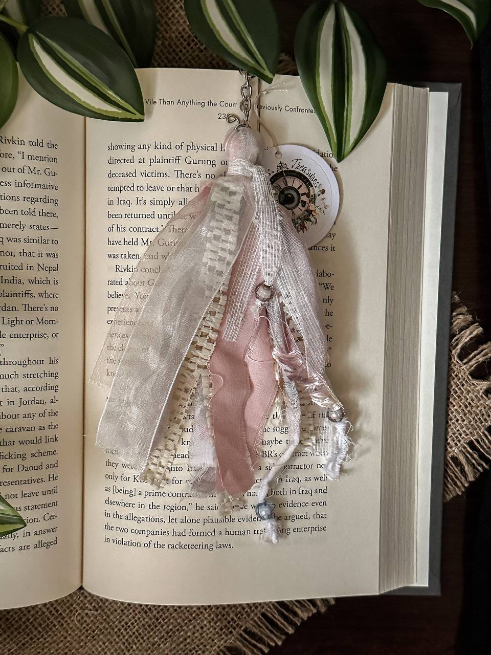Handmade Boho tassel paperclip bookmark from Suzys Treasures, featuring pink and off white lace ribbons, pearl bead accents, and crochet trim, displayed on an open book – a charming and versatile accessory for journals, planners, or novels.
