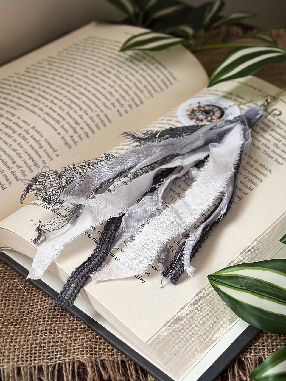 Handmade Boho tassel paperclip bookmark from Suzys Treasures, featuring black and white lace ribbons, pearl bead accents, and crochet trim, displayed on an open book – a charming and versatile accessory for journals, planners, or novels.
